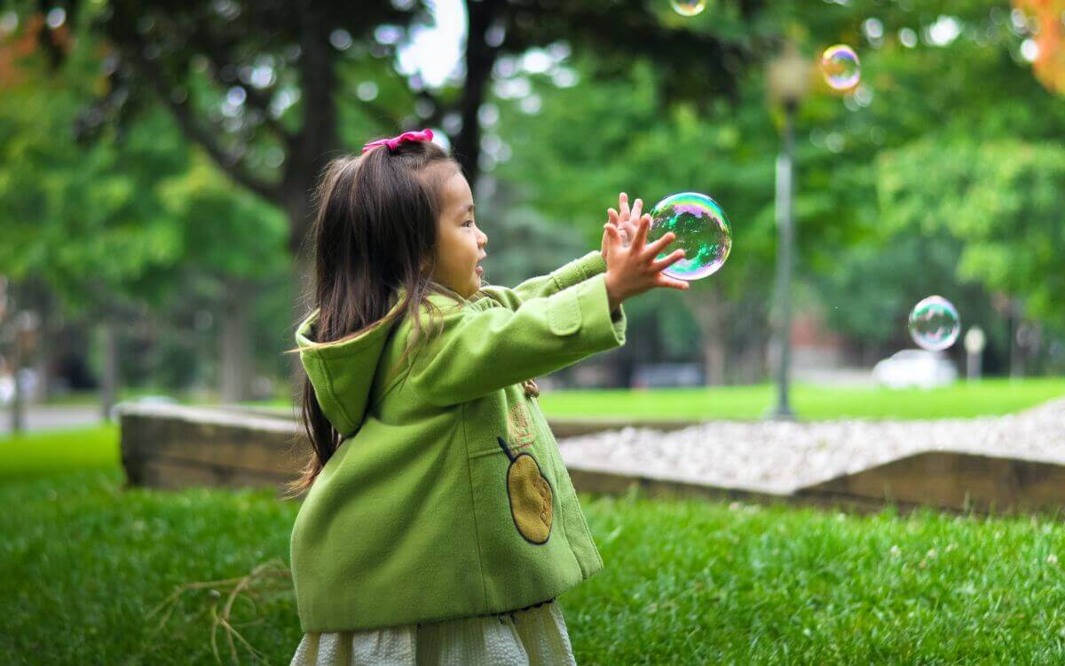 Girl catching bubbles outside