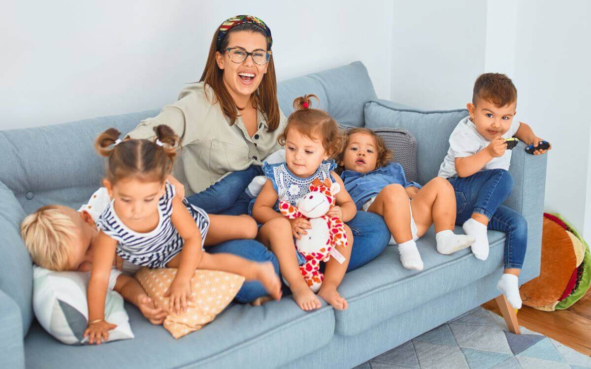 happy female teacher siting on a sofa with children