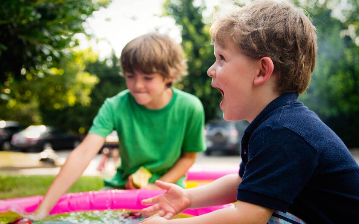 Two boys playing with a small inflatable pool