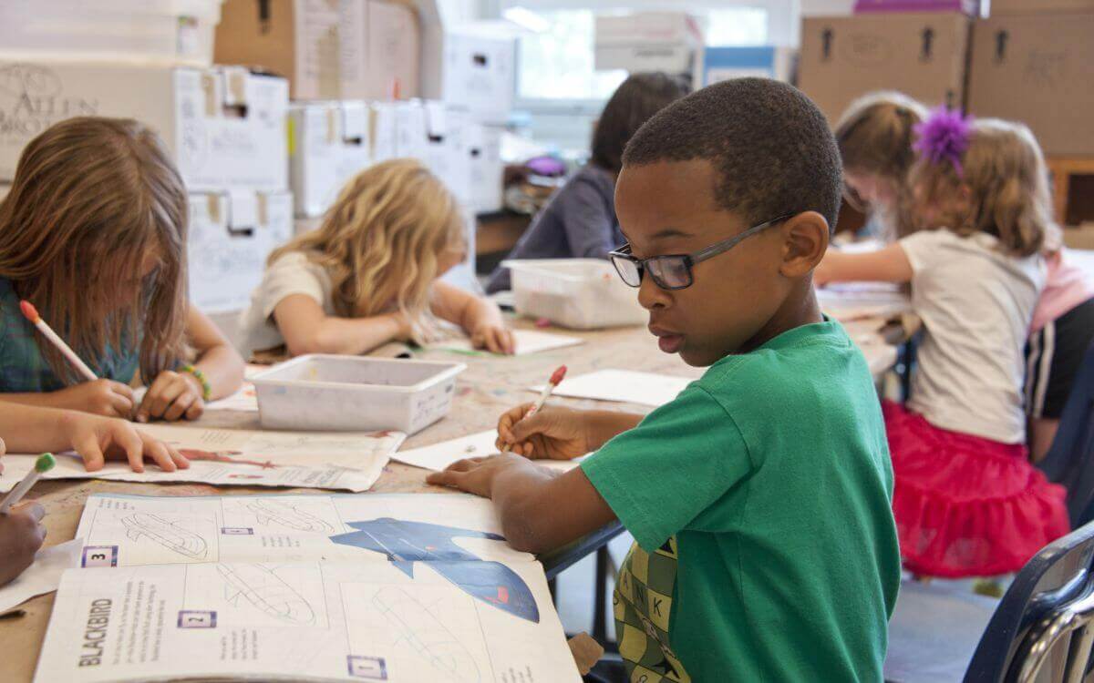 Children in a classroom writing in notebooks