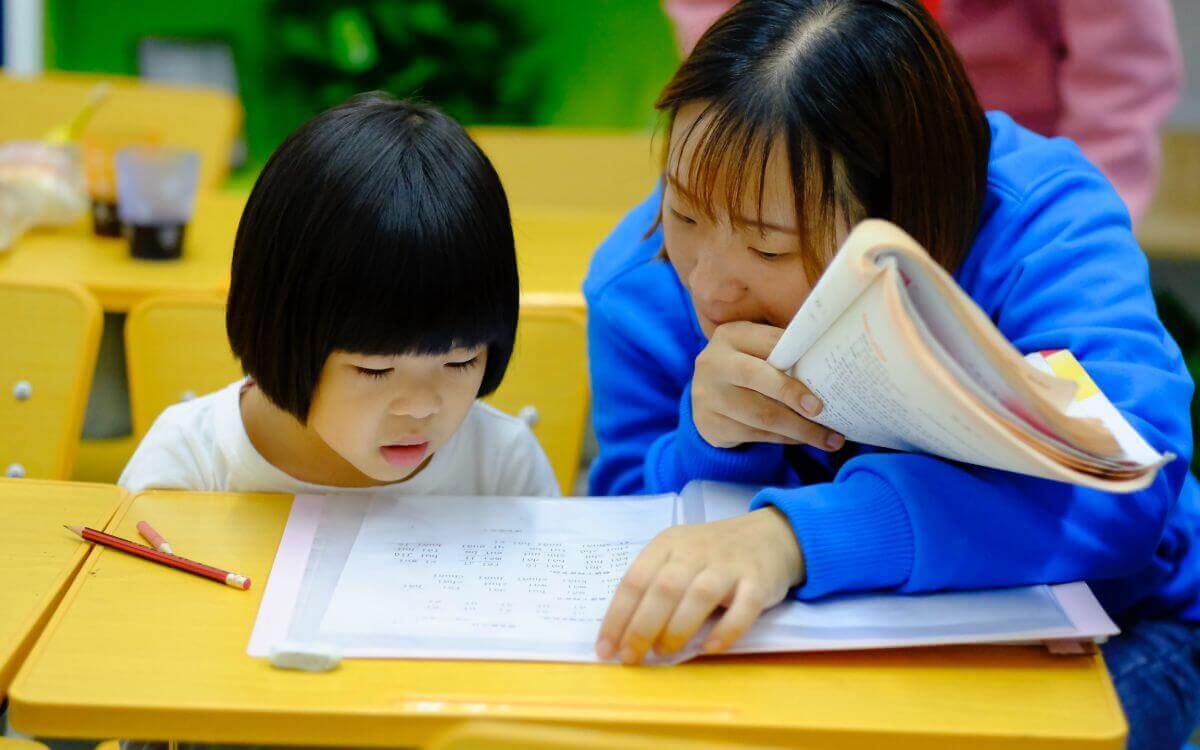 Teacher assistant checking classwork of a girl student