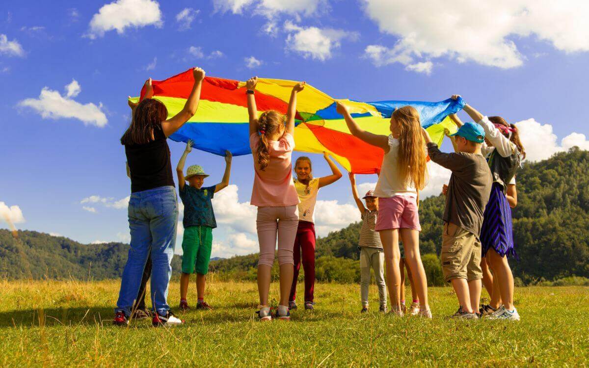 Children playing with colorful parachute in a field